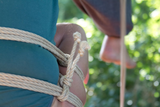 Shibari in nature in summer. Bound young girl.
