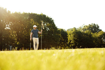 Male golfer putting flag in hole at golf course