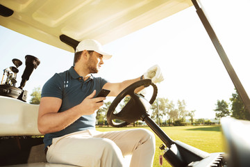 Young sportsman driving golf cart