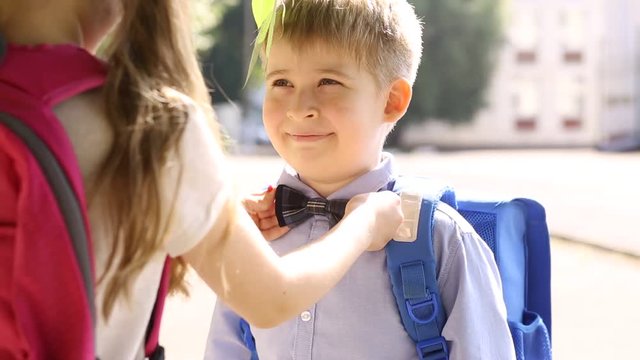 The sister corrects the bow tie to her younger brother. Children at school.
