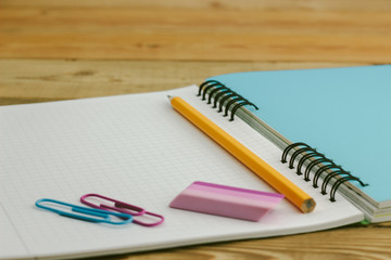 green notebook on a wooden table with pencils