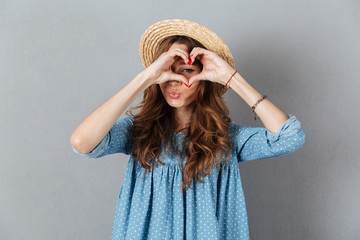 Happy young pretty woman showing heart gesture. Looking camera.