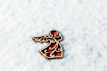 Red wooden toy angel on snow