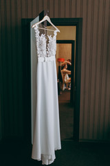 A beautiful wedding dress hanging in a room