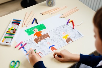Fototapeta na wymiar Child draws a pastel drawing of his teacher in school class.