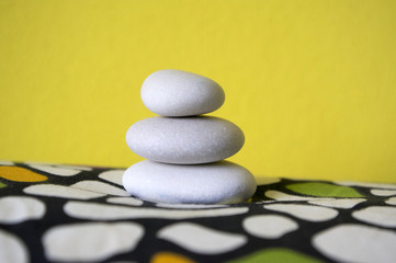 Harmony and balance, cairn, poise stones, rock zen sculpture, three white pebbles, yellow background