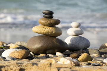 Fototapeta na wymiar Harmony and balance, poise stones against the sea, rock zen sculpture, sunny day, two towers - light and dark, sandy beach