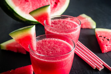 Fresh watermelon drink in glasses with slices of watermelon on dark table