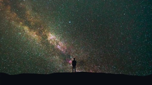 The man stand on a background of a milky way with asteroids skyfall. time lapse
