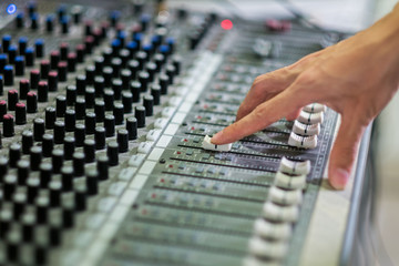 Close up hands of sound engineer working at mixing panel in recording studio.