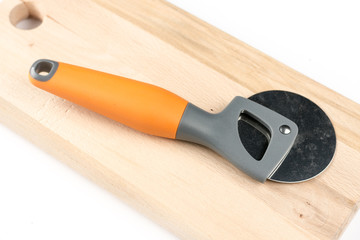 Black and orange round pizza knife on the cutting wooden board
