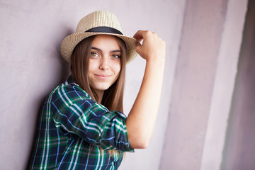 Beautiful young woman in hat near pink wall