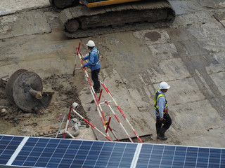 workers in construction area with crane truck and holding machine