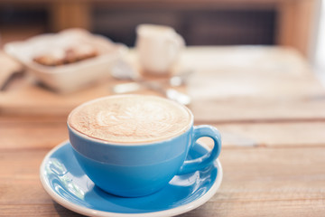 Latte art coffee in blue cup on wooden table in coffee shop