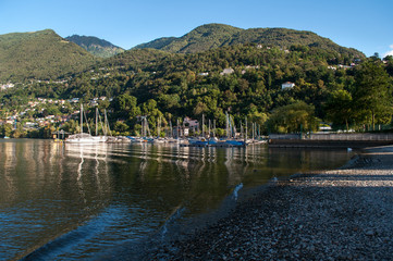 Lake Locarno - lake shore with pebble beach and high mountains of swiss alps in the background.