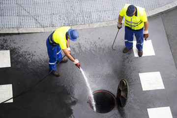 sewer line drainage  by utilities workers with hose with pressurized water