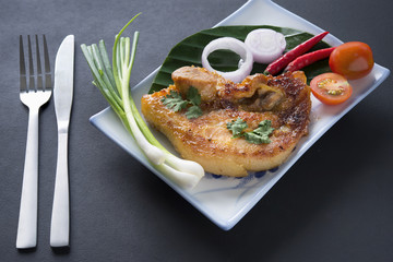 Grilled Pork on banana leaf and dish with black background, thai food,