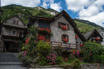 Fototapeta na wymiar Sonogno small town in the swiss mountains. Street with old stone houses decorated with flowers.