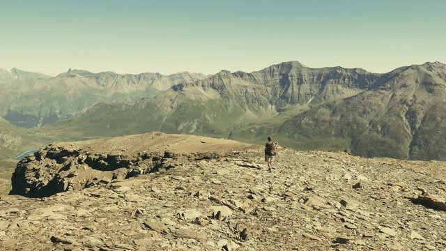 Woman walking in high altitude rocky mountain landscape. Summer adventures on the Italian French Alps. Slow motion, old retro vintage filter.