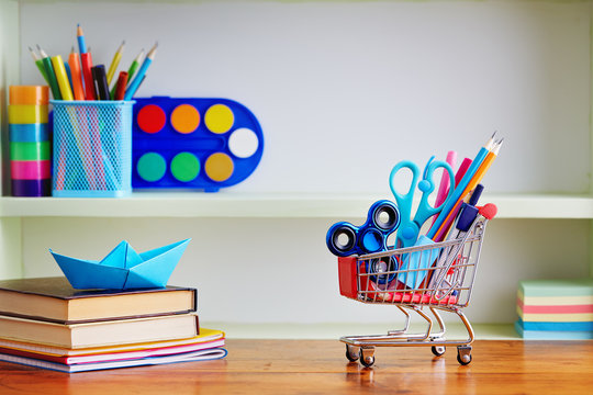 Back to School Shopping Cart with Supplies on Wooden Table.