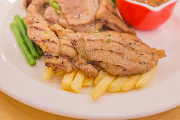 Close up grilled roast pork beef steak with french fries and vegetables and yardlong bean on white plate
