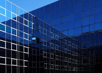 Two modern glass facades that intersect and reflect themselves