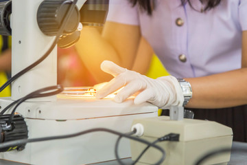 Student girl looking through microscope in science laboratory study research experiments about...
