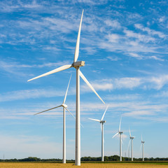 A wind farm located amid the fields generates renewable electricity by the power of the wind.