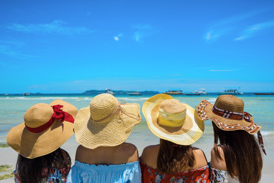 Young four woman group in hawaii dress with hat on sea beach summer fun and happy leisurer, elax in vacation time.