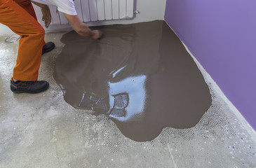 Worker puts a self leveling screed with trowel on concrete floor