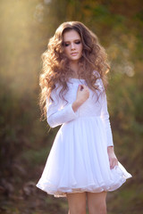 Beautiful young girl with makeup and hair-dress on a background of autumn forest
