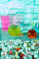 A large variety of medicinal pills on the background of the test tubes and flasks