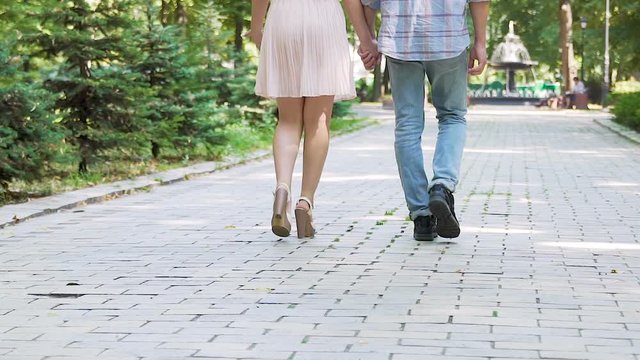 Romantic date of young man and woman, couple in love walking in summer park