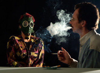 A man smoking a cigarette blowing smoke on a woman in a gas mask