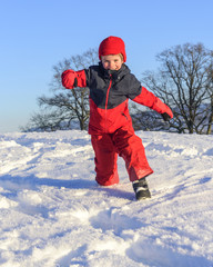 Fototapeta na wymiar fröhlicher Junge laufend im Schnee