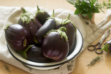 Aubergines in a bowl on a wooden table. Vertical. Selective focus.