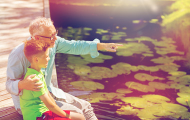 grandfather and grandson sitting on river berth