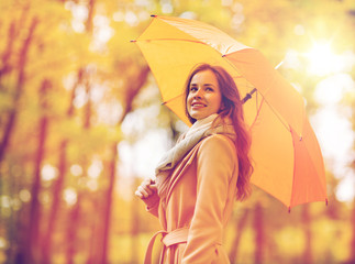 happy woman with umbrella walking in autumn park