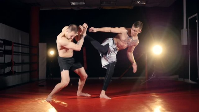 A fighter knocks down his assistant with a jump kick. 