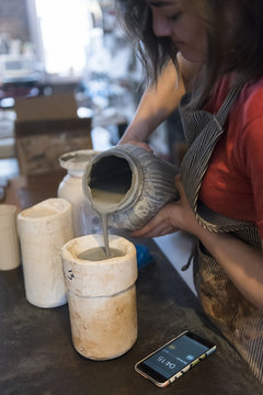 Caucasian woman pouring clay into pottery mold