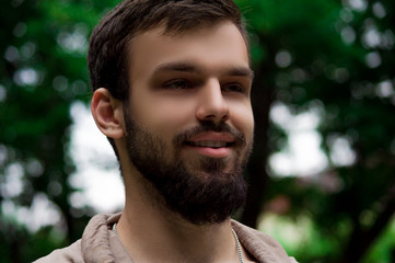 Close-up Portrait of young man with a beard smiling. outside in the park