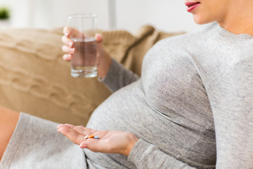 close up of pregnant woman with pills at home