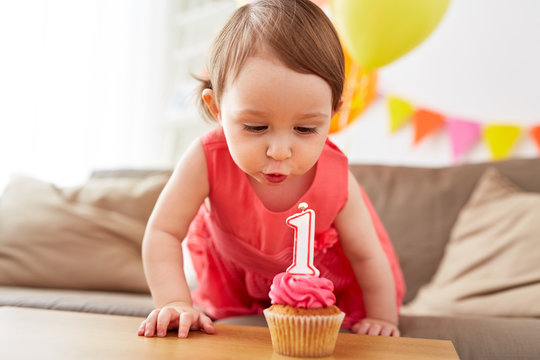 Girl Blowing To Candle On Cupcake At Birthday