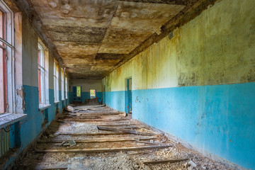 Fototapeta na wymiar Ruined Long Corridor Of Abandoned School After Chernobyl Nuclear
