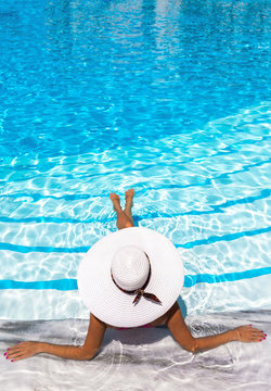 Frau mit weißem Hut entspannt in einem Pool