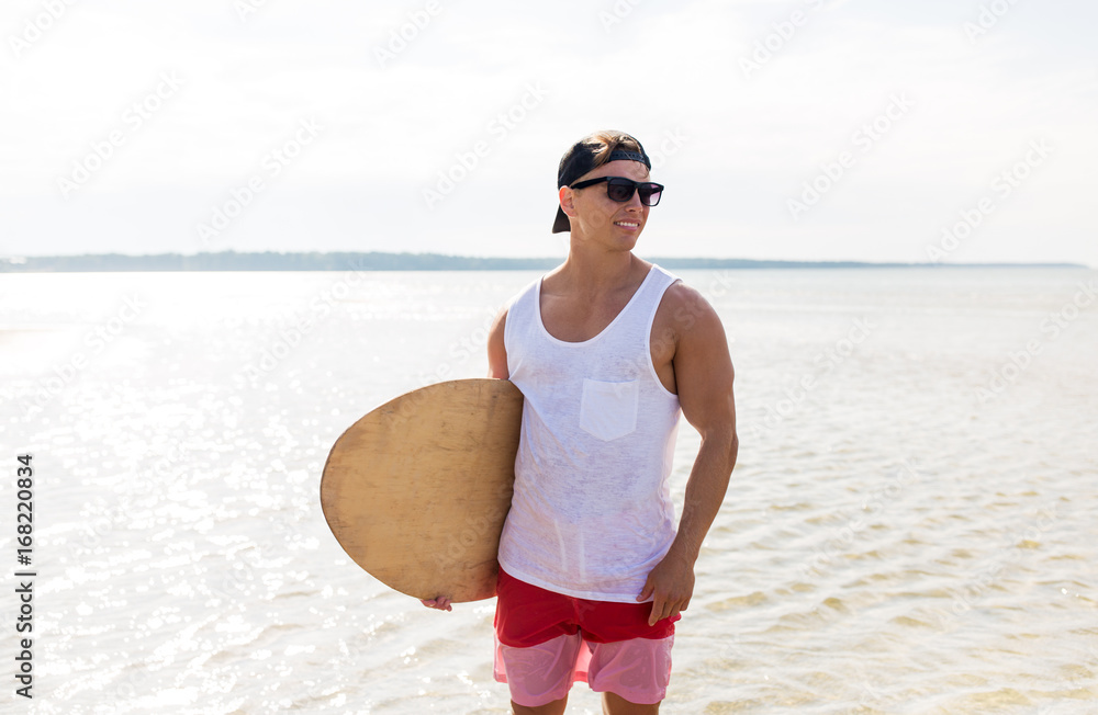 Wall mural happy young man with skimboard on summer beach