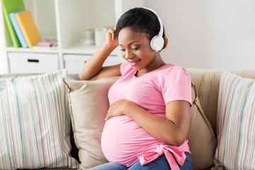 pregnant woman in headphones at home