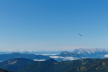 Fototapeta na wymiar small prop plane above Mountains in Bavaria, view from Mt. Hochfelln on a summer day sunrise