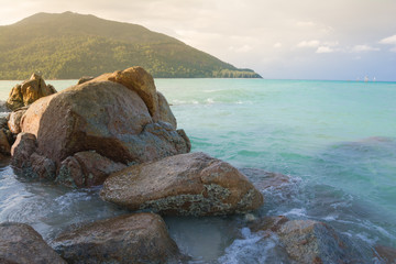 Fototapeta na wymiar Splash waves hit rocks with the beautiful sunlight and sky .