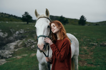 Woman is walking with a white horse in the mountains in nature